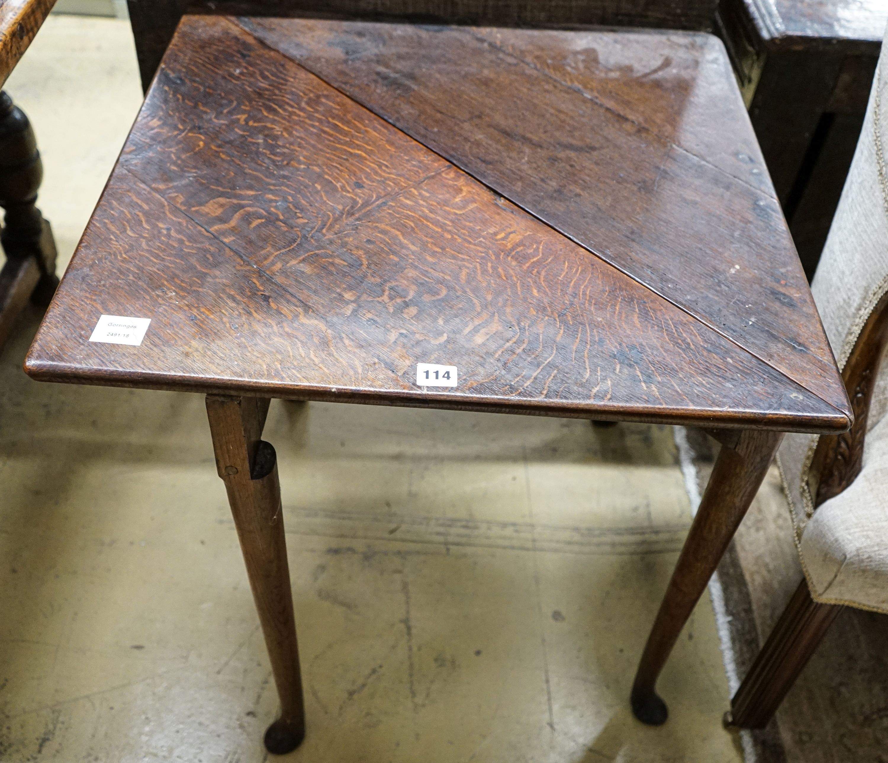A George II oak folding top tea table, with triangular flap, on turned legs and pad feet, 64cm extended, depth 64cm, height 68cm